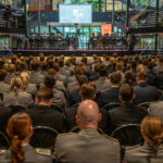 Studierende der HSU/UniBw H sitzen in Paradeuniformen im Foyer der HSU. Sie sind von hinten zu sehen.