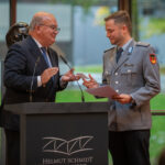 Prof. Dr. Klaus Beckmann gratuliert einem Preisträger, einem schlanken Soldaten in grauer Paradeuniform.